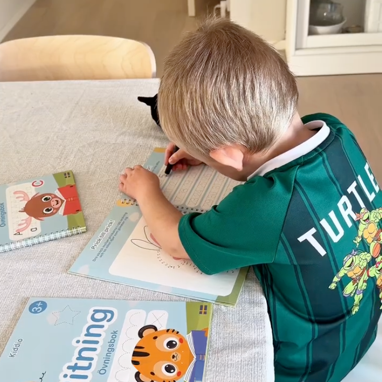 Boy writing in the Drawing book at the table