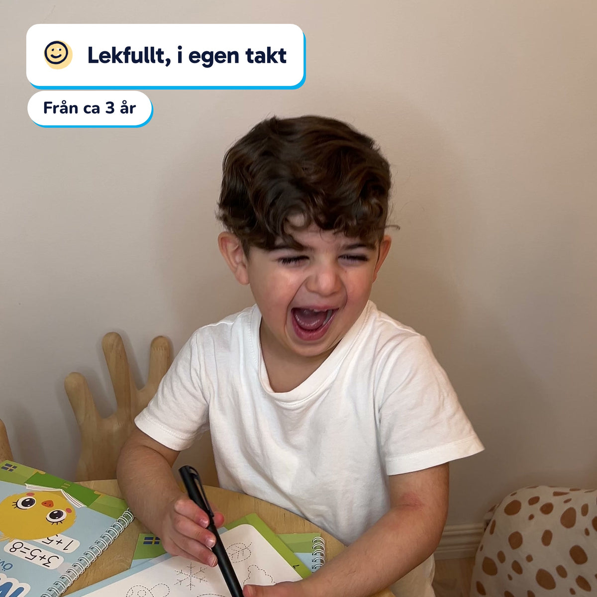 Pojke skrattar medan han övar i övningsboken, från ca 3 år