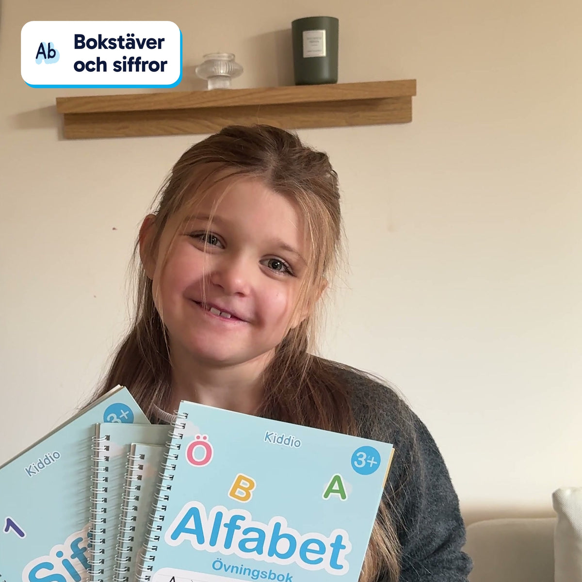 Flicka håller upp de magiska övningsböckerna hemma