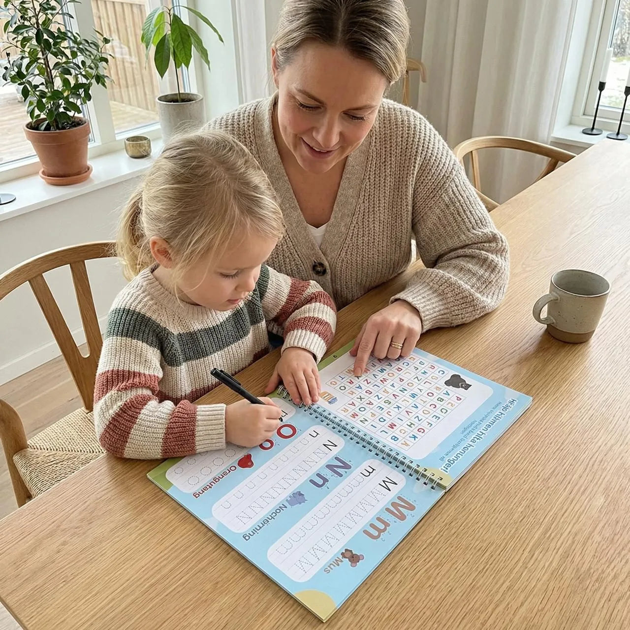 Mamma och dotter övar bokstäver i Kiddios övningsbok vid köksbordet