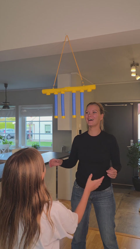 A family plays the Kiddio Reflex Game at home, catching the falling sticks