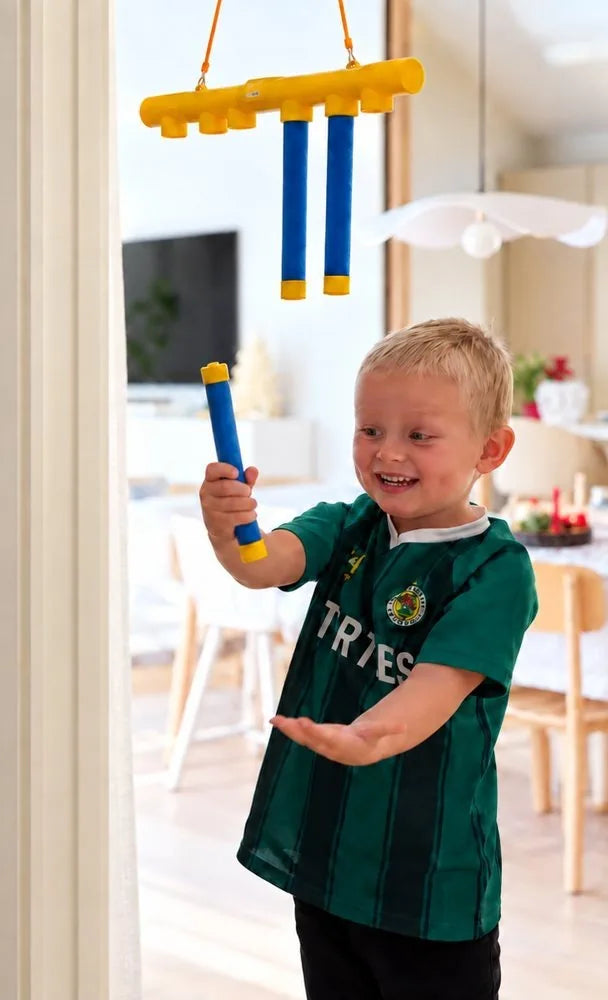 Pojke fångar en pinne från Reflexspelet hemma i vardagsrummet